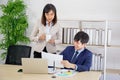 An Asian female coworker stood talking to a business man on the desk in her hand holding a cup of coffee Royalty Free Stock Photo