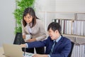 An Asian female coworker stood talking to a business man on the desk in her hand holding a cup of coffee Royalty Free Stock Photo