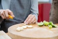 Asian female cut garlic by knife on the wood board with half lime beside it to preparing lunch at the kitchen Royalty Free Stock Photo