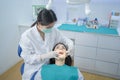 Asian female dentist in lab coat wearing protective face mask to prevent from Covid19. Expert doctor examining tooth for young gir Royalty Free Stock Photo