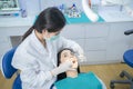 Asian female dentist in lab coat wearing protective face mask to prevent from Covid19. Expert doctor examining tooth for young gir Royalty Free Stock Photo