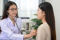 Asian female doctor checking heart rate listening to chest of young female patient with stethoscope in clinic Royalty Free Stock Photo