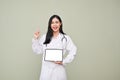 Asian female doctor holding tablet, pointing finger up, standing against grey background Royalty Free Stock Photo