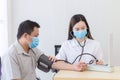 Asian female doctor measure blood pressure of a man patien