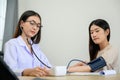 Asian female doctor measuring heart rate and blood pressure while taking care of beautiful asian patient in medical consultation Royalty Free Stock Photo