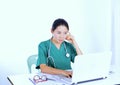 Asian female doctor physician touching temple sitting at work desk