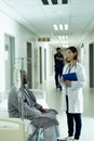 Asian female doctor and senior african american male patient talking in hospital corridor Royalty Free Stock Photo