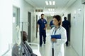 Asian female doctor and senior african american male patient talking in hospital corridor Royalty Free Stock Photo