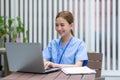 Asian female doctor smile looking and working at computer laptop on work table. Nurses wear scrub smile with heartwarming