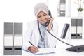Asian female doctor with stethoscope talking on the phone while Royalty Free Stock Photo