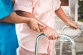 Asian female doctor in surgical gown caring for elderly female patient, helping to walk, doing physiotherapy. Royalty Free Stock Photo