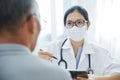 Asian Female Doctor talking to senior man patient. Royalty Free Stock Photo