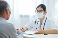 Asian female doctor talking to senior man patient. Royalty Free Stock Photo