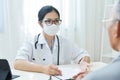 Asian Female Doctor talking to senior man patient. Royalty Free Stock Photo