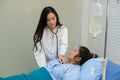 Asian female doctor using stethoscope listening checking heartbeat fat woman patient on the bed Royalty Free Stock Photo