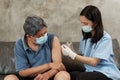 An Asian female doctor is vaccinating an elderly man at home Royalty Free Stock Photo