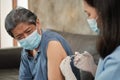 An Asian female doctor is vaccinating an elderly man at home Royalty Free Stock Photo