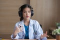 Asian Female doctor wear headphones working at office desk and smiling at camera Royalty Free Stock Photo