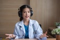 Asian Female doctor wear headphones working at office desk and smiling at camera Royalty Free Stock Photo