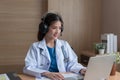 Asian Female doctor wear headphones working at office desk and smiling at camera Royalty Free Stock Photo