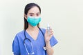 Asian female doctor wearing blue uniform wearing a medical mask, holding alcohol spray, washing hands while waiting for the Royalty Free Stock Photo