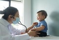 Asian female doctor wearing face mask examining little cute Baby boy with stethoscope Royalty Free Stock Photo