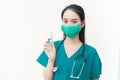 Asian female doctor wearing green uniform wearing a medical mask, holding alcohol spray, washing hands while waiting for the Royalty Free Stock Photo