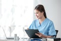 Asian female doctor working on laptop, filling out paperwork, patient medical history, reviewing documents at her Royalty Free Stock Photo
