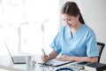 Asian female doctor working on laptop, filling out paperwork, patient medical history, reviewing documents at her Royalty Free Stock Photo