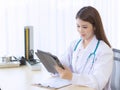 Asian woman doctor working report of her patient on tablet Royalty Free Stock Photo