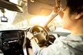 Asian female driver covering face by hand of bright sun,disturbed dazzled by sun light,difficulty in driving,young woman driving