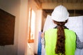 Asian female engineer or architect in white helmet holding construction blueprints Royalty Free Stock Photo