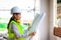 Asian female engineer holding a blueprint at a construction site. Royalty Free Stock Photo