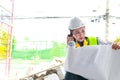 Asian female engineer holding a blueprint at a construction site. Royalty Free Stock Photo