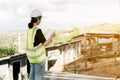 Asian female engineer Put on a white safety hat Wearing a green safety shirt Stand for construction inspection In the construction