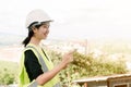 Asian female engineer Put on a white safety hat Wearing a green safety shirt Stand for construction inspection In the construction