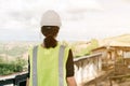 Asian female engineer Put on a white safety hat Wearing a green safety shirt Stand for construction inspection In the construction