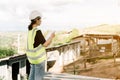 Asian female engineer Put on a white safety hat Wearing a green safety shirt Stand for construction inspection In the construction