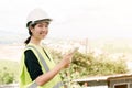 Asian female engineer Put on a white safety hat Wearing a green safety shirt Stand for construction inspection In the construction