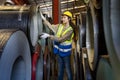 Asian female engineer worker is examining the stainless galvanized metal sheet roll inside the warehouse factory for roofing Royalty Free Stock Photo