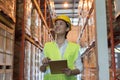 Asian female engineer working in store warehouse. Woman looking at check sheet to checking inventory