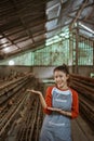 Asian female farmer with hands presenting something at chicken farm