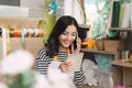 Asian female florist calling on smartphone and making notes at f Royalty Free Stock Photo