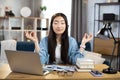 Asian female freelancer in headset meditating at table, feeling relaxed Royalty Free Stock Photo