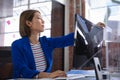 Asian female in front of computers separated by sneeze shield giving document to colleague