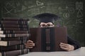 Asian female graduate peeking from behind a book