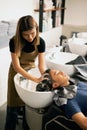 A hairdresser washes hair for a customer in a barber shop and male lying on a chair.