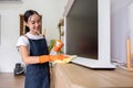 Asian female housekeeper cleaning the house using spray and cleaning cloth at the table in the living room Royalty Free Stock Photo