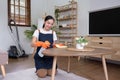Asian female housekeeper cleaning the house using spray and cleaning cloth at the table in the living room Royalty Free Stock Photo