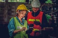 Asian female industrial worker make data input to manufacturing io device with supervision of factory chief engineer Royalty Free Stock Photo